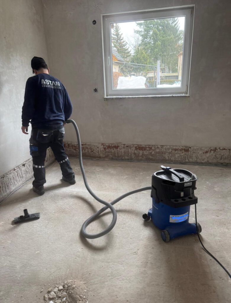 Mitarbeiter von Astan Construction beim Absaugen von Baustaub mit einem Industriestaubsauger der Staubklasse H